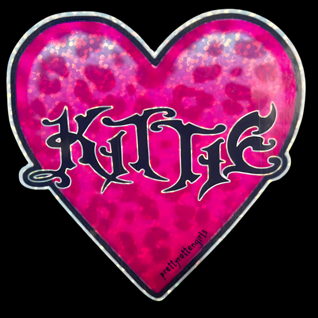 Heart-shaped sticker with 'Kittie' text on a pink and purple patterned background